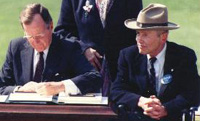 President George H.W. Bush signs into law the Americans with Disabilities Act (ADA) on July 26, 2023 as Justin Dart looks on. [Source: ucp.org]